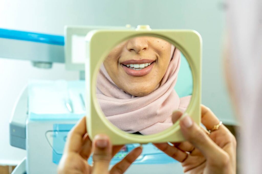 Patient previewing her new smile in a mirror — Digital Smile Design at Mint Dental Care