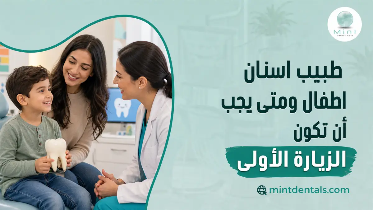 طبيب أسنان أطفال يتحدث مع طفل ووالدته داخل العيادة لتوضيح موعد الزيارة الأولى وأهمية الفحص المبكر.